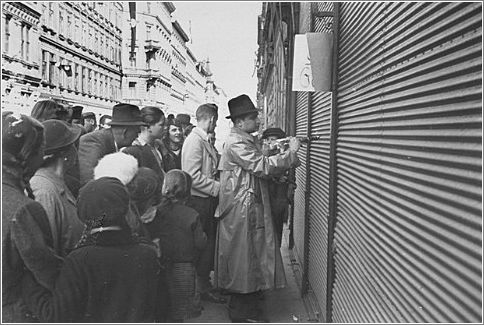A Jewish man forced to paint anti-Jewish graffiti on a shuttered storefront. Vienna, Austria, March 1938.